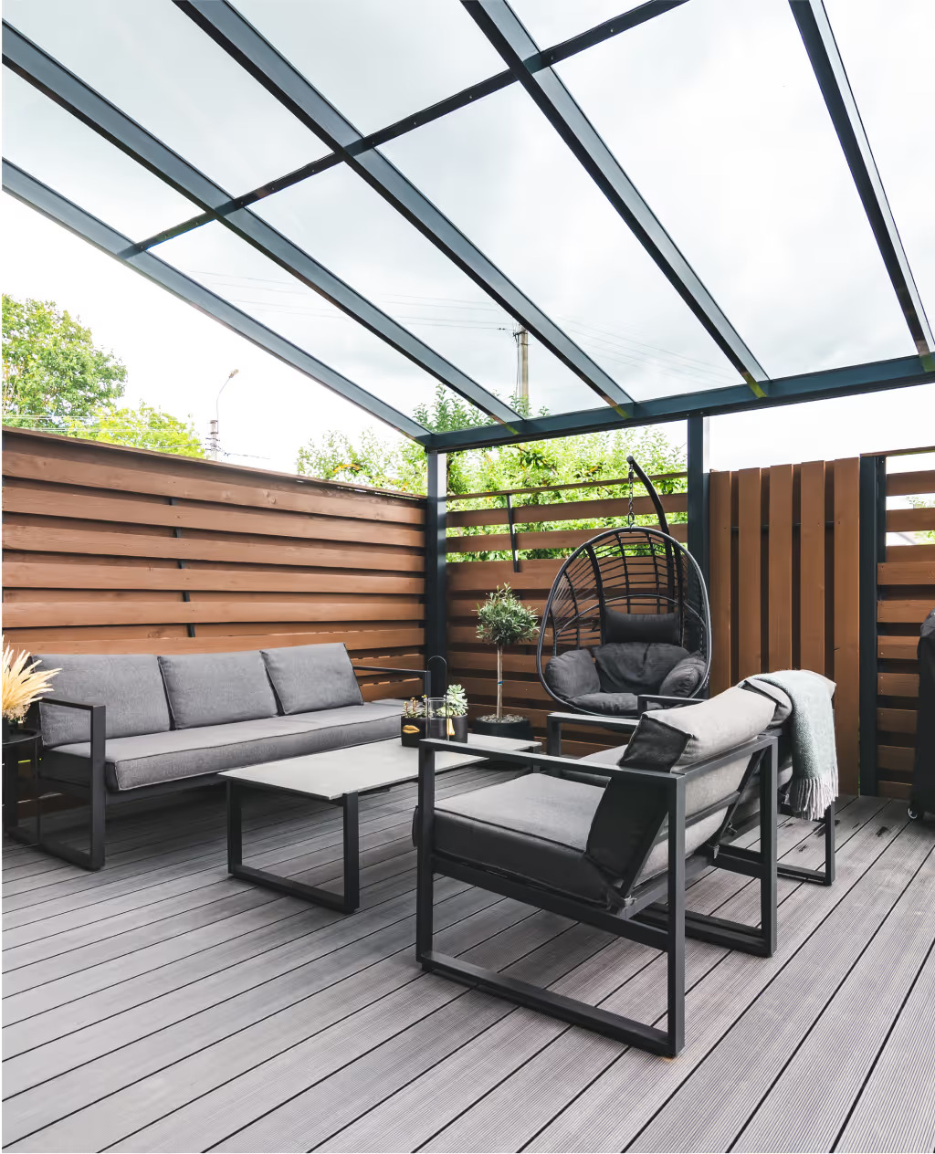 A wooden patio with grey furniture